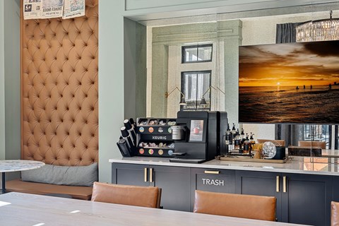 A bar area with a brown tufted headboard and a counter with a Keurig coffee machine.