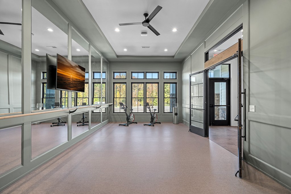A spacious fitness studio room with a ceiling fan and a large screen on the wall.