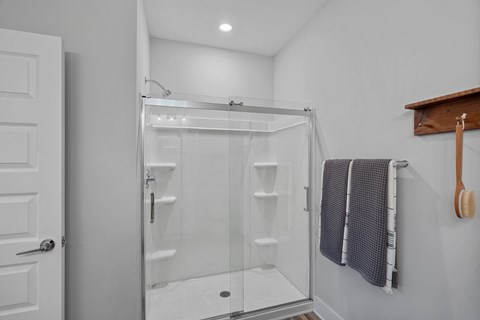 A white bathroom with a glass shower stall and a white door.