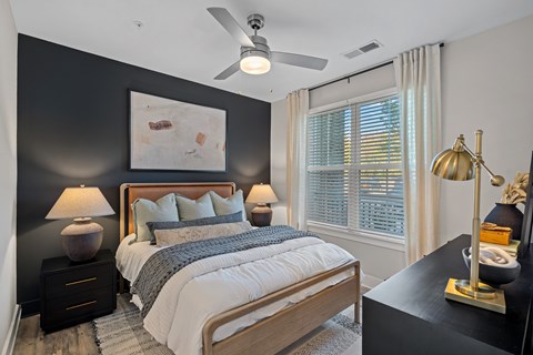 A Bedroom with a Large bed, a Ceiling Fan, and a painting on the wall.