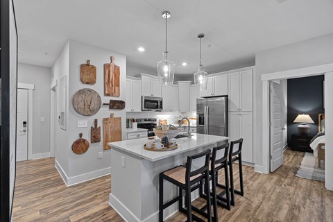 A kitchen with a white island and wooden floors with an open door to the bedroom.