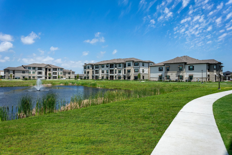 a walkway next to a pond with apartments in the background
