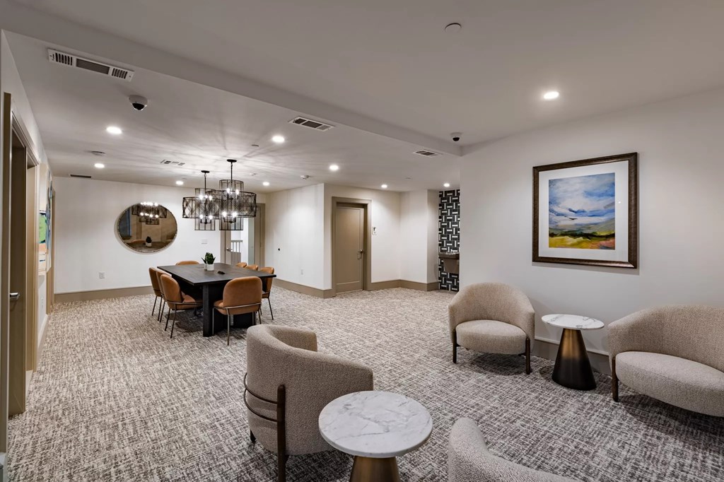 A room with a dining table, chairs, and a painting on the wall.