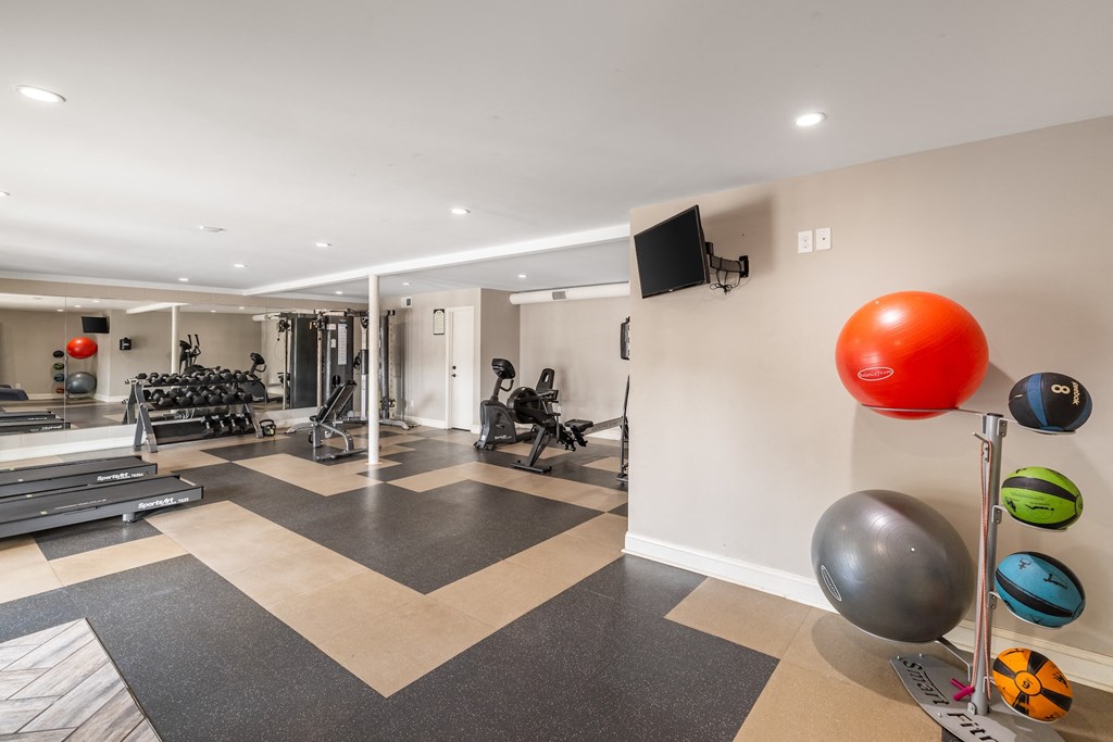 A gym with a variety of equipment including weights and exercise balls.