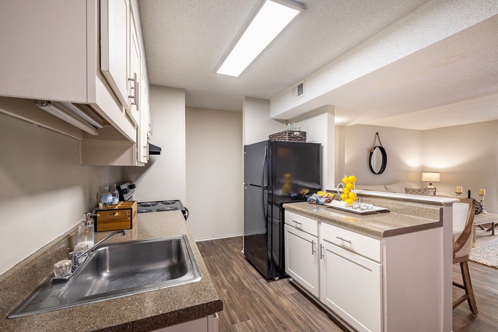 A kitchen with a black refrigerator and white cabinets.
