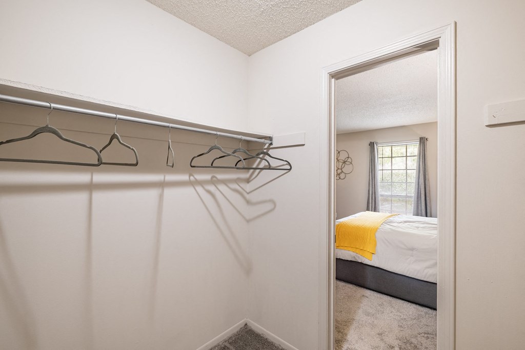 A white bedroom with a bed, a window, and a mirror.