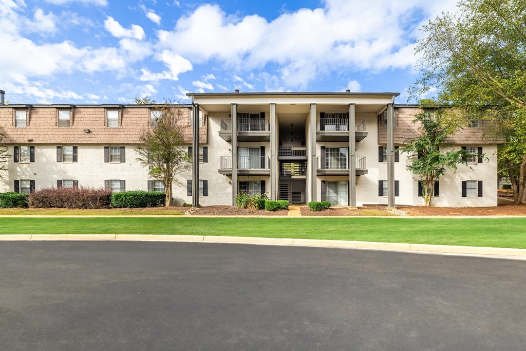 A large apartment building with a parking lot in front.