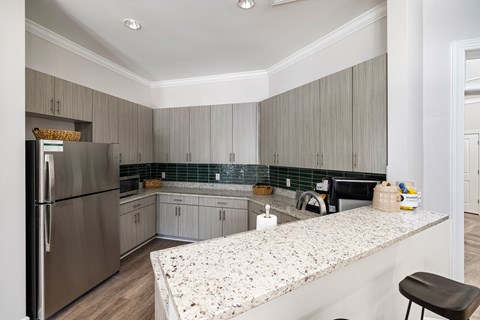 A Kitchen with a Granite Countertop and a Stainless Steel Refrigerator.