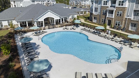 Large Swimming Pool Surrounded by Lounge Chairs and Umbrellas.