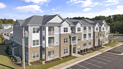 Exterior of Complex with Grey and White Coloring and a Parking Lot in Front.