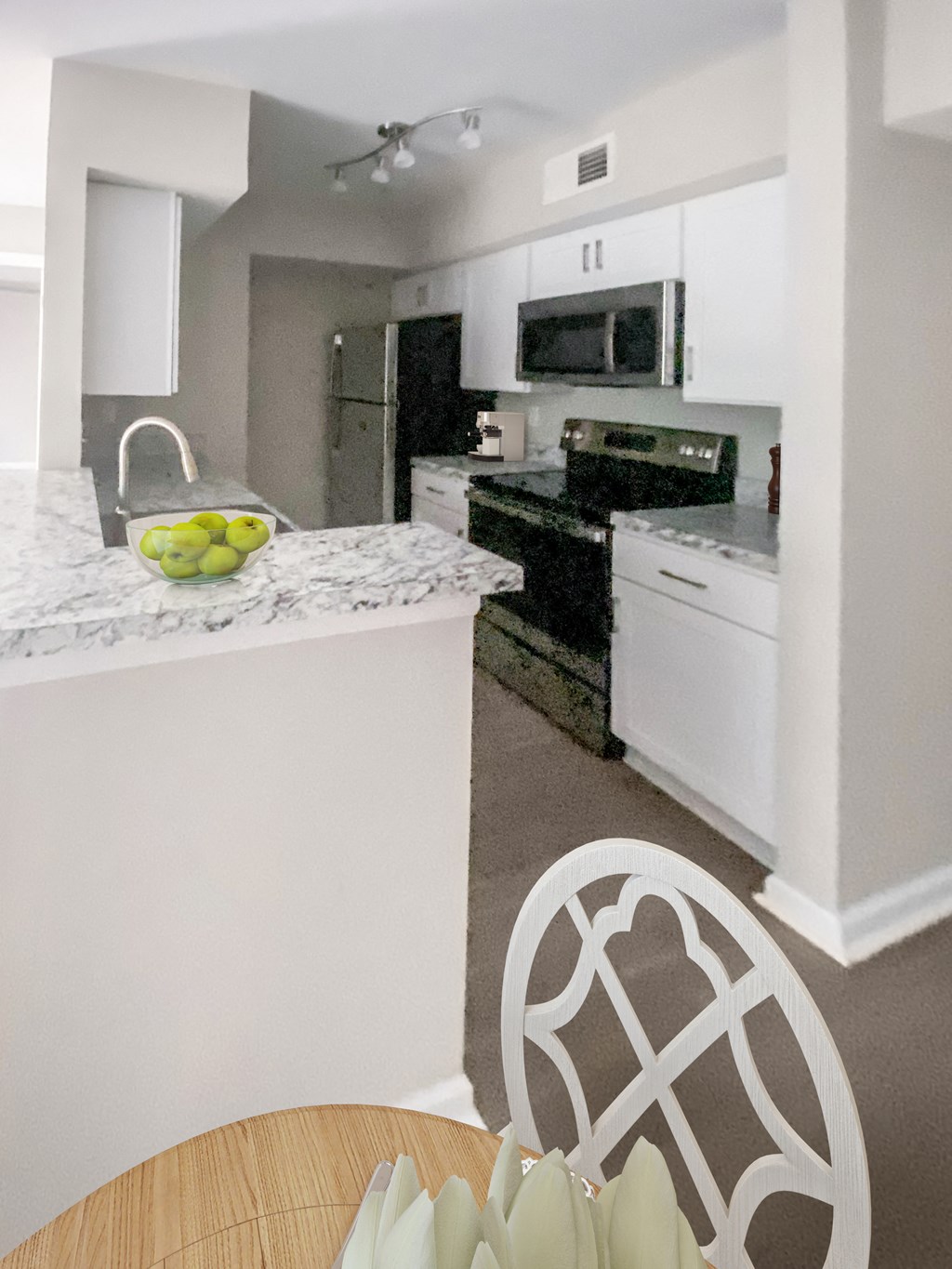 a white kitchen with a marble counter top and white appliances