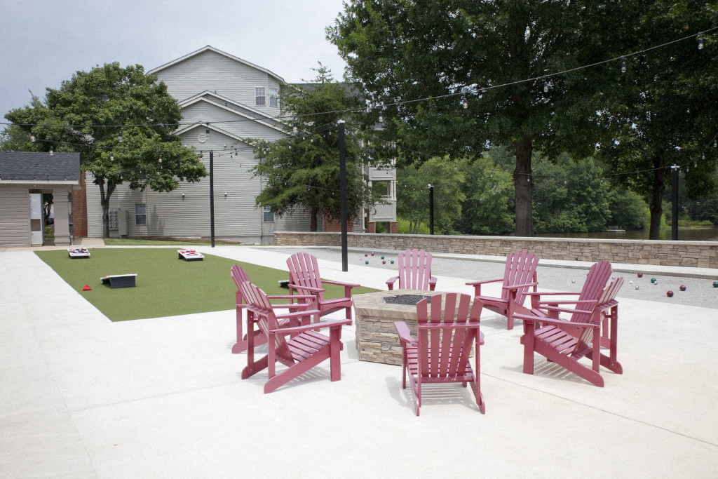 a group of pink chairs around a table on a patio next to a pool