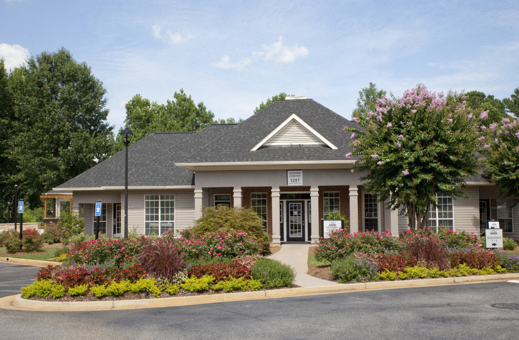 the front of a building with flowers and bushes in front of it