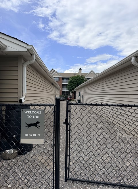 A sign that says "Welcome to the Dog Run" is on a fence.