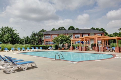 A pool with chairs and a building in the background.