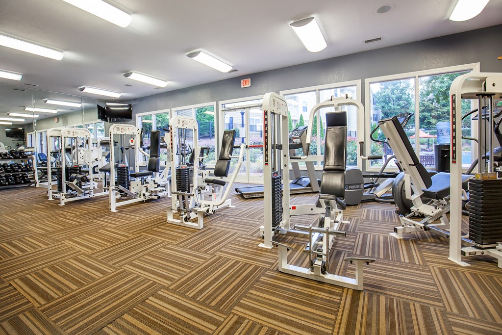 a gym with cardio machines and weights on a wooden floor