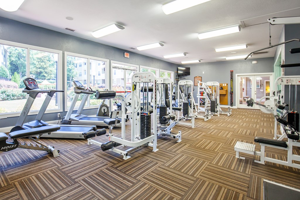 a gym with cardio machines and weights on a wooden floor