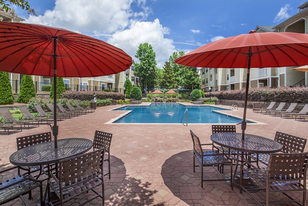 a swimming pool with umbrellas and tables with chairs