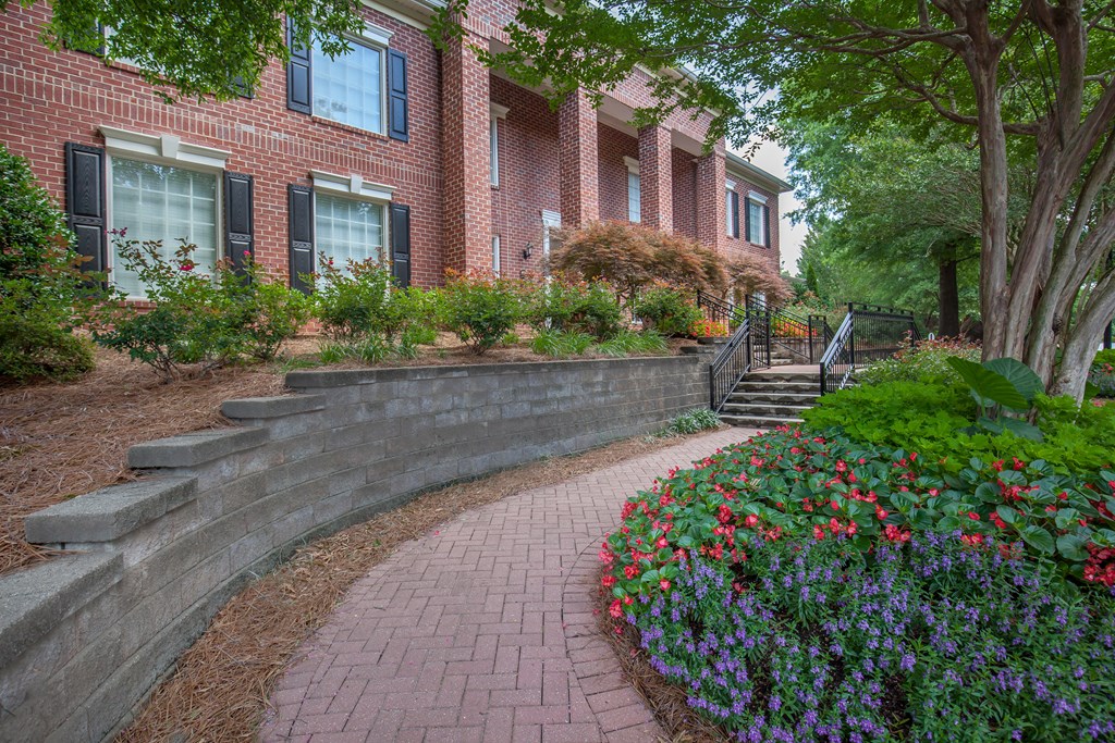 a walkway in front of a brick building with flowers