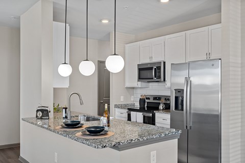 A modern kitchen with granite countertops and stainless steel appliances.