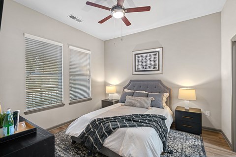 A bedroom with a bed, nightstands, and a ceiling fan.