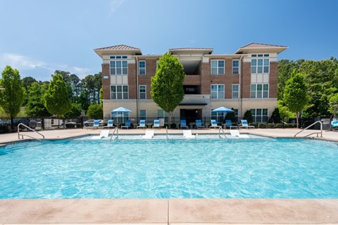 A large swimming pool in front of a multi-story apartment building.