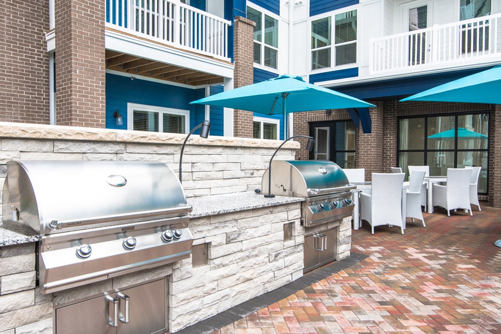 a patio with a grill and a bar with tables and umbrellas