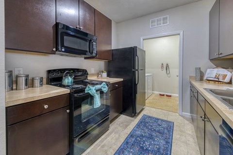 A kitchen with brown cabinets and a black refrigerator.