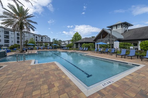 A large outdoor swimming pool surrounded by lounge chairs and umbrellas.