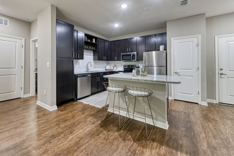 A kitchen with black cabinets and a granite countertop.
