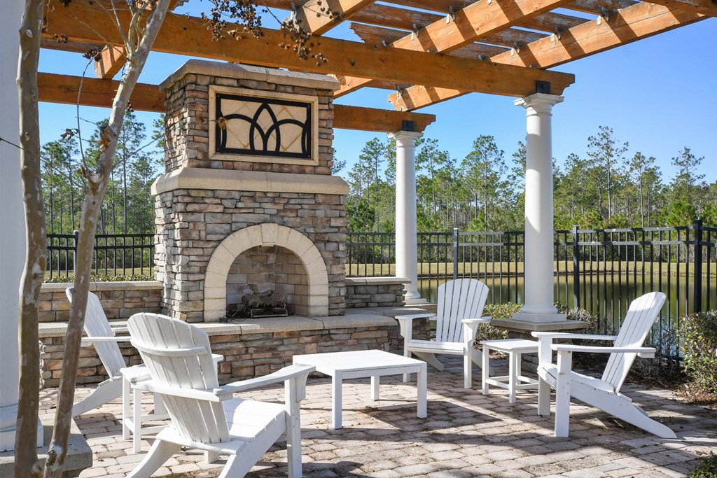 a patio with a stone fireplace and tables and chairs