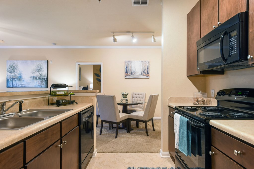 a kitchen with a stove and a sink and a dining room