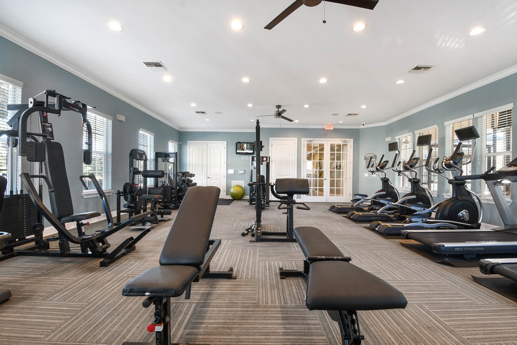 a gym with weights and cardio equipment on the floor and windows