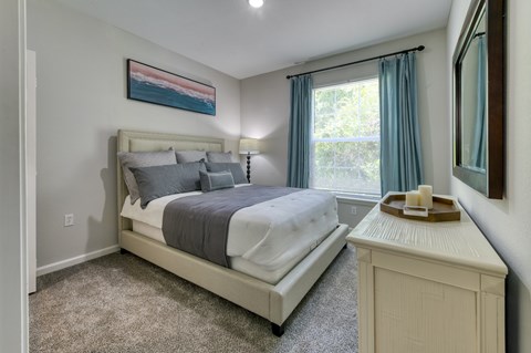 A bedroom with a large bed and a painting on the wall.