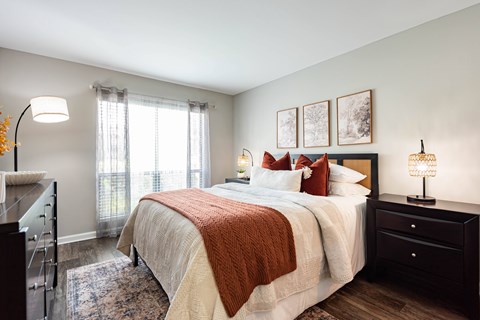 A bedroom with a large bed and a window with curtains.