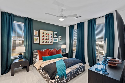 A bedroom with a bed, nightstand, and a ceiling fan.