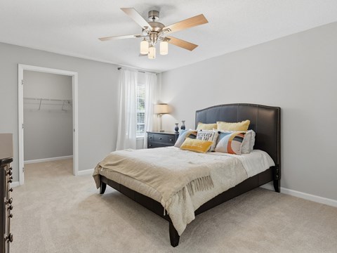 A bedroom with a bed, a ceiling fan, and a window with curtains.
