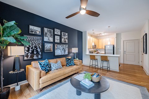 A living room with a beige couch and a ceiling fan.