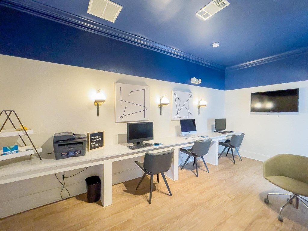 a home office with two computers and a tv