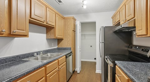 A kitchen with wooden cabinets and a black refrigerator.