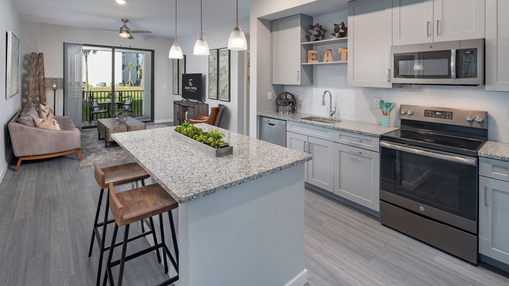 an open kitchen and living room with a marble counter top
