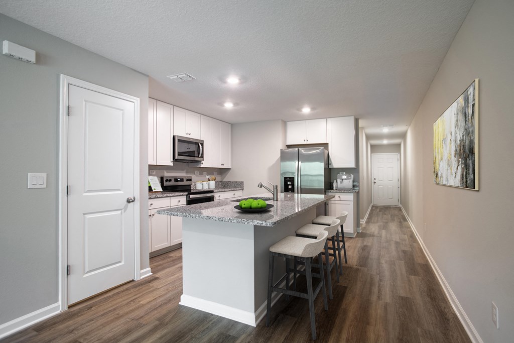 an open kitchen with a large island with a granite counter top