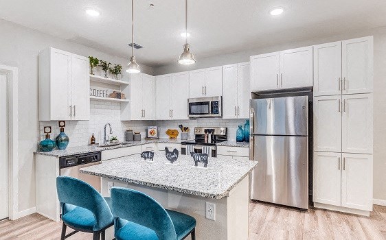 a kitchen with a marble counter top and a stainless steel refrigerator