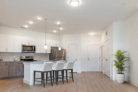 an open kitchen with white cabinets and a large island with white chairs