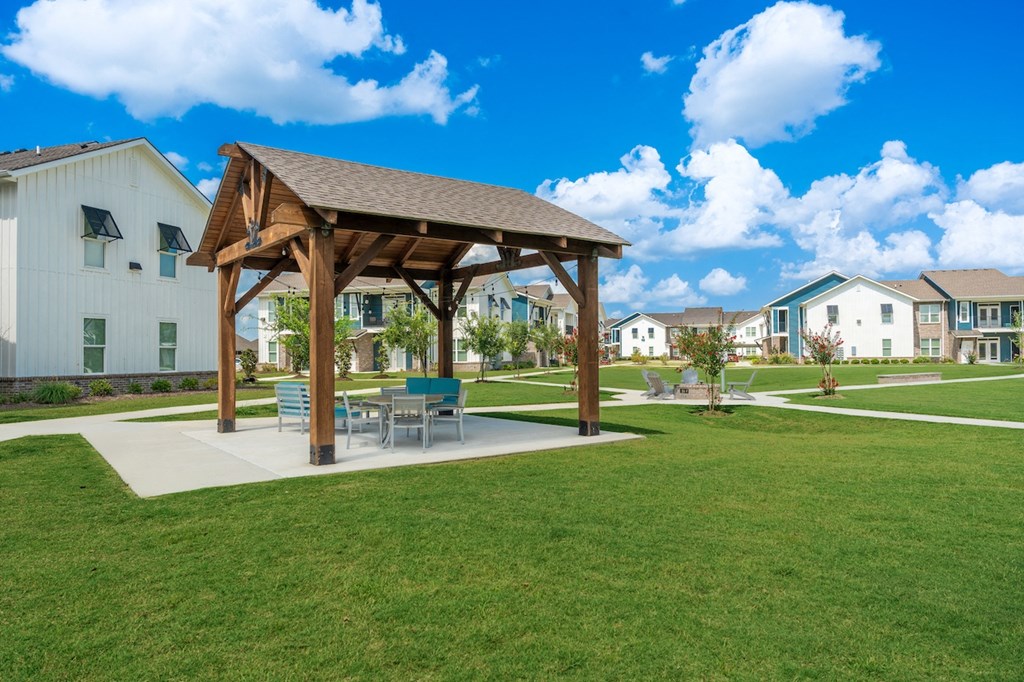 a pavilion with a table and chairs in the middle of a grassy area
