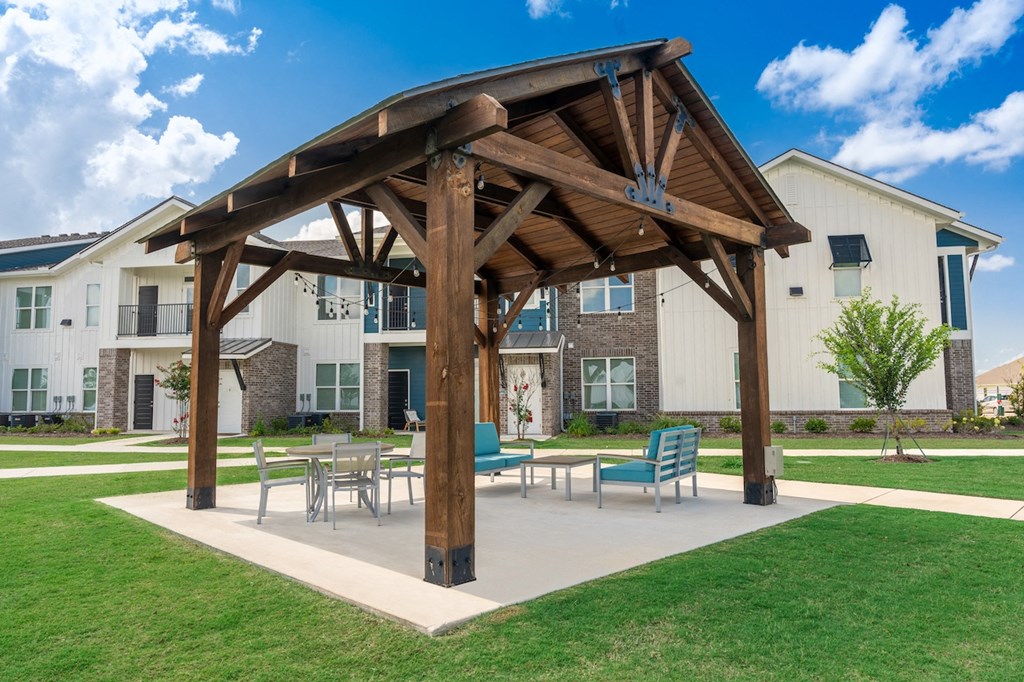an outdoor patio with a wooden pavilion and tables and chairs