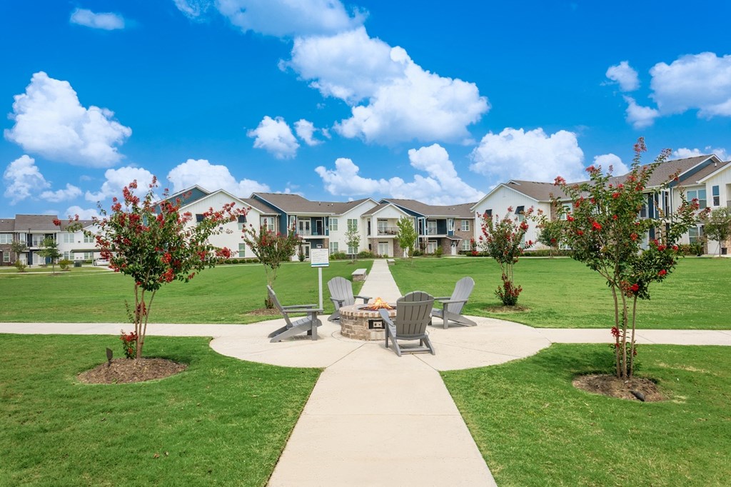 a patio with a fire pit and chairs in front of a row of houses