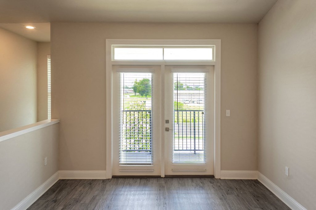 an empty living room with a glass door and a balcony