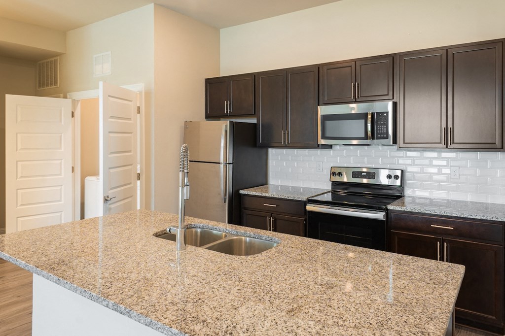 a kitchen with granite countertops and black cabinets