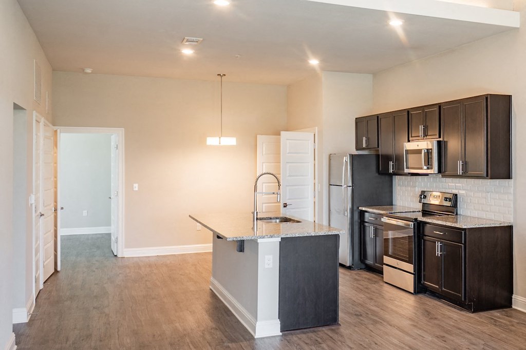 a kitchen with black cabinets and a stainless steel refrigerator